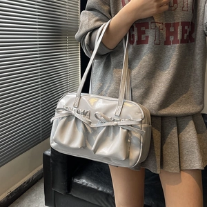 Large glossy light grey tote bag with bow pockets shown on shoulder for a chic commute style