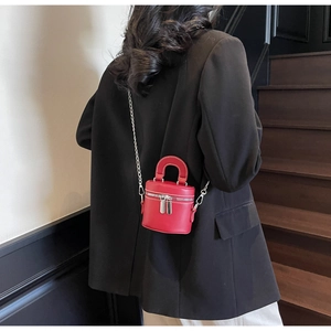 Close-up of red mini bucket bag with white stitching and silver chain worn with black blazer