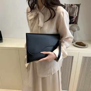 Fashionable black matte leather saddle-style clutch bag with wrist strap for women