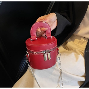 Détail du sac cylindrique rouge avec chaîne argentée et surpiqûres blanches