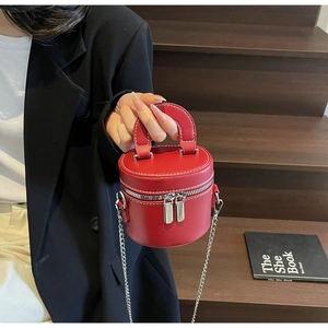 Détail du sac boîte cylindrique rouge avec surpiqûres contrastées et zip en métal argenté