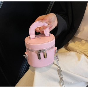 Détail d'un mini sac vanity rond rose avec chaîne argentée et poignée en cuir