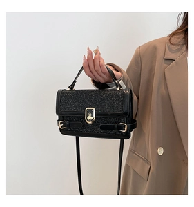 Detail of glittery black fabric texture and golden metal twist lock on the handbag