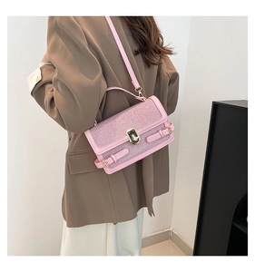 Detail of pink glitter handbag with gold twist lock shown on model for size and fit