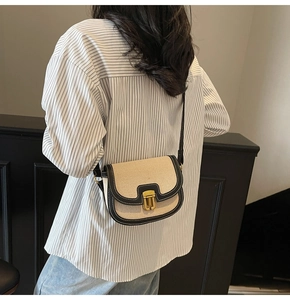 Detail of vintage beige canvas saddle bag with black leather trim and gold metal buckle