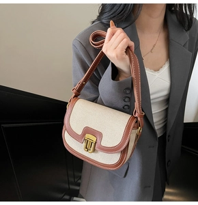 Detail of retro canvas saddle bag with brown leather trim and vintage gold metal clasp