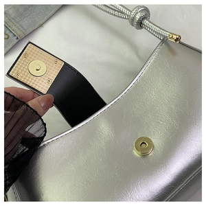 Détail du sac baguette argenté avec fermoir magnétique doré et bandoulière corde