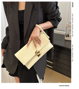 Detail showing beige envelope bag with vertical texture and gold geometric buckle
