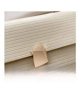 Detail of cream envelope clutch with horizontal texture and gold geometric buckle