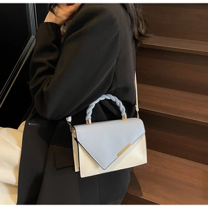 Detail of light blue and beige contrast crossbody bag with braided handle and gold trim