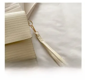 Detail of cream white textured leather handbag with gold metal hardware and wrist strap