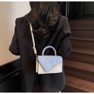 Detail of light blue and white contrast bag with woven handle and asymmetric flap