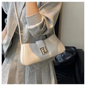 Détail du sac baguette gris clair avec boucle dorée sur une tenue en tricot
