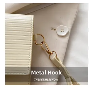 Macro view of cream textured leather handbag featuring premium gold hardware hooks