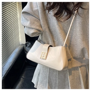 Gros plan d'un sac baguette crème avec une boucle métallique dorée géométrique