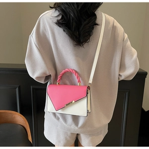 Pink and white colorblock handbag with woven handle worn as a crossbody bag