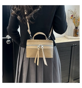 Close-up of beige woven texture crossbody bucket bag featuring long tassel double zippers