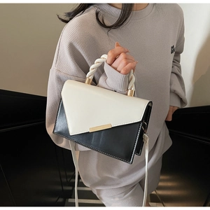 Detail view of contrast black and white crossbody bag with braided handle and gold buckle