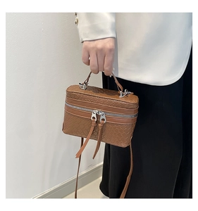 Detailed view of brown woven texture and dual zipper design on a structured box bag
