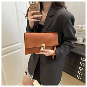 Detail of caramel brown epi leather clutch with golden lock held by a model