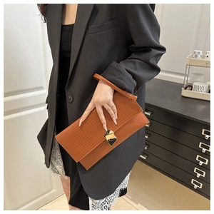 Detail of caramel textured envelope clutch with gold geometric buckle and wrist strap