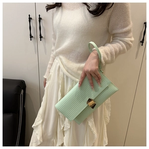 Close-up of mint green textured leather handbag with a gold triangular metal buckle