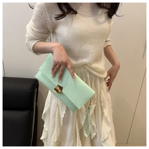 Detail of mint green envelope clutch with vertical pleats and golden clasp closure