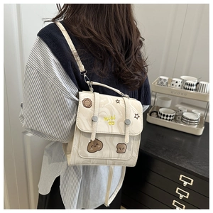 Close-up of beige marble pattern backpack with cute cartoon embroidery and metal clasp