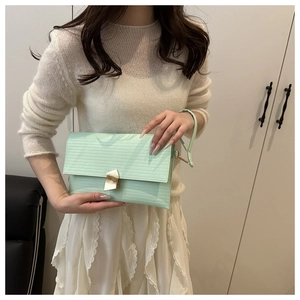 Detailed macro view of mint green envelope clutch with textured faux leather and gold clasp