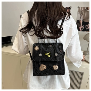 Detail of black glossy backpack featuring yellow miai to embroidery and cute cartoon patches