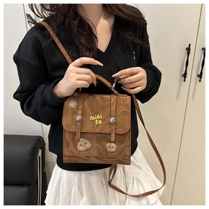 Detail of a brown marble texture PU bag with yellow letters and cartoon bread patches