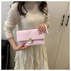 Detail view of pink textured envelope clutch with gold metal buckle and leather wrist strap