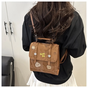 Close-up of brown glossy mini backpack featuring yellow miai to embroidery and star patch
