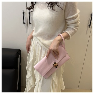 Pink minimalist clutch bag with textured finish and golden buckle held by hand