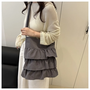 Detail of dark gray canvas tote bag featuring triple-layered ruffle pleats and wide strap