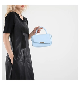 Vista lateral del pequeño bolso cuadrado azul claro de cuero con elegante hebilla dorada