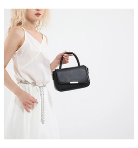 Detalle del bolso de mano negro minimalista con hebilla dorada y asa superior resistente
