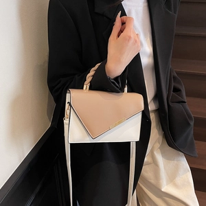 Chic color-block handbag with woven handle and gold hardware on a fashion model