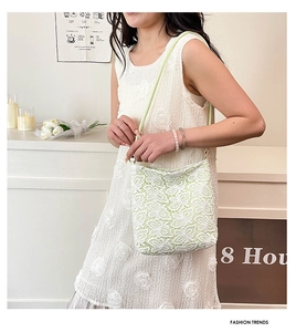 Close-up of light green lace shoulder bag with floral embroidery and elegant strap