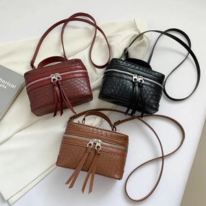 Three stylish woven leather bucket bags in burgundy, black, and caramel with long tassels