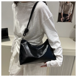 Détail du sac hobo en cuir PU noir brillant avec un noeud élégant sur la bandoulière
