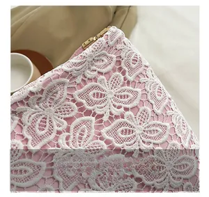 Close-up of pink lace fabric with white floral embroidery and golden metal zipper detail