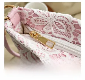 Macro detail of the smooth gold zipper and white floral lace texture on a pink shoulder bag