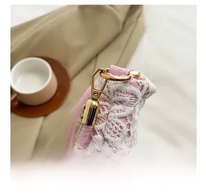 Detailed close-up of pink leather bag with white lace overlay and gold metal hardware