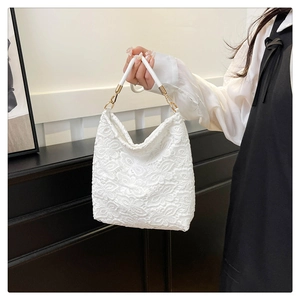 Close-up of white floral lace handbag featuring intricate 3D patterns and gold chain details