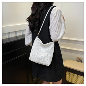 Detail of elegant white floral lace shoulder bag with intricate cutout patterns and soft texture