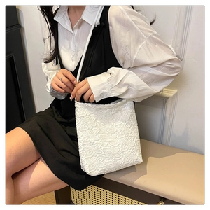 Detailed view of elegant white lace shoulder bag featuring intricate floral textures