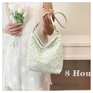 Detail view of light green lace shoulder bag with floral lace overlay and metal hooks