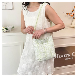 Detail of floral butterfly embroidery on white lace tote bag with light green straps