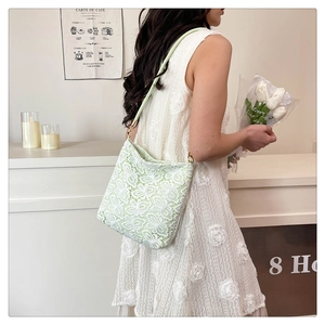 Detail of light green shoulder bag with delicate white floral lace and slim handle